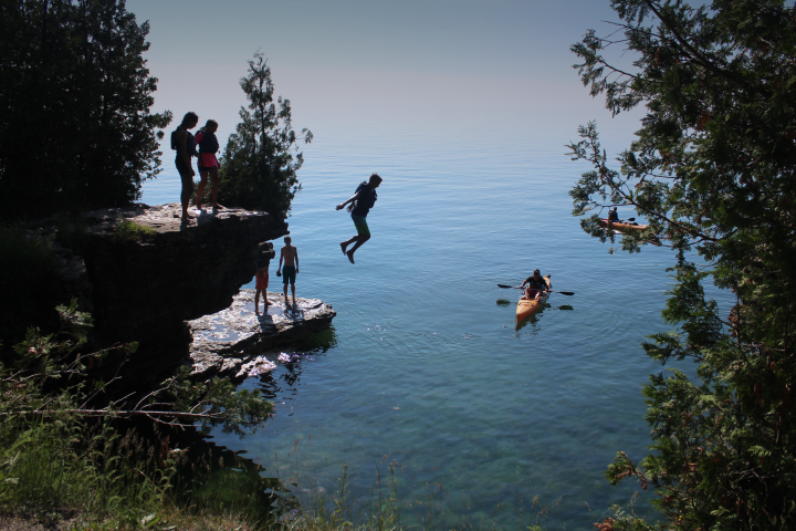 Kayaker jumping off bluff into water in Door County, Wisconsin